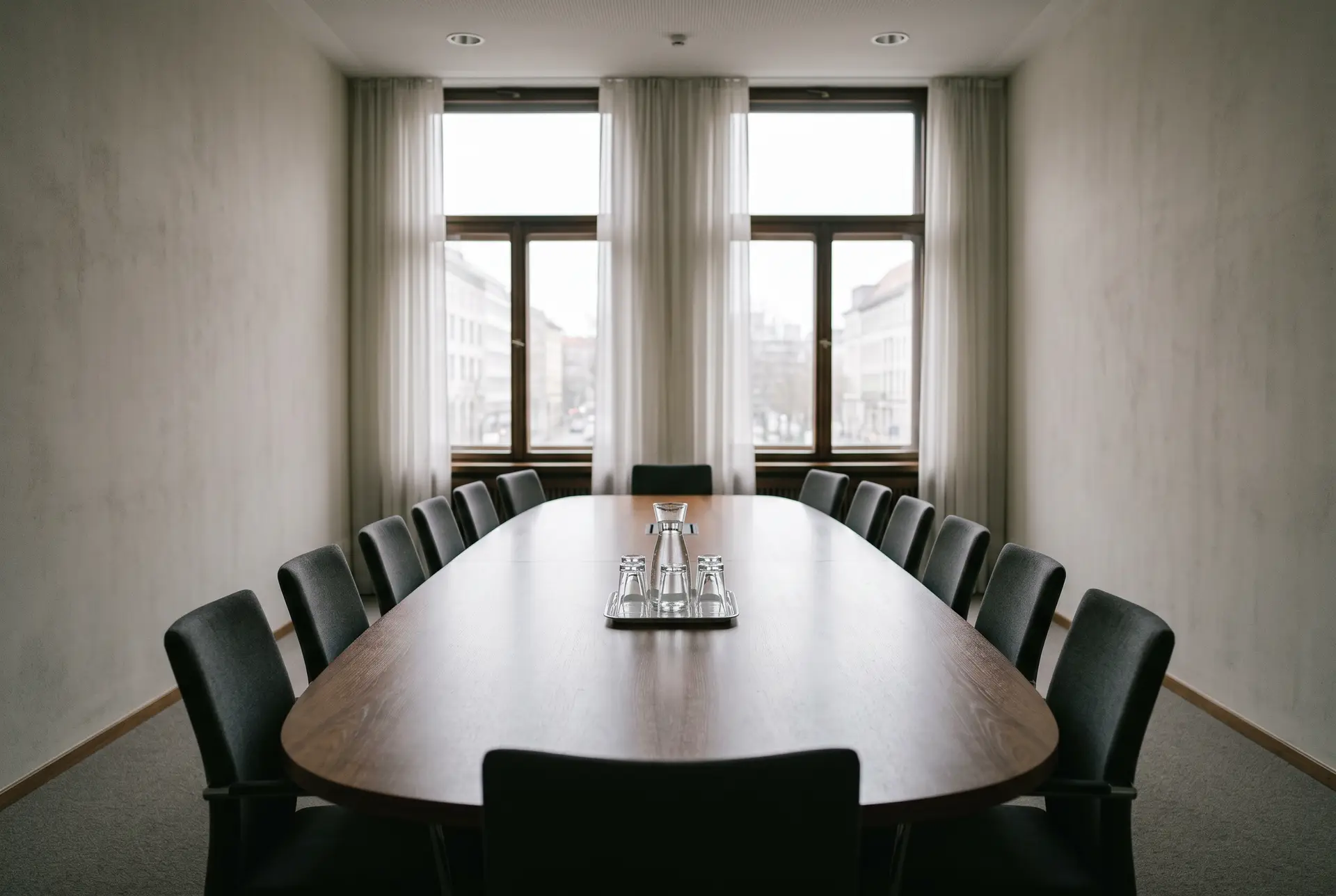 Leerer Sitzungssaal mit ovalem Konferenztisch und Fensterfront